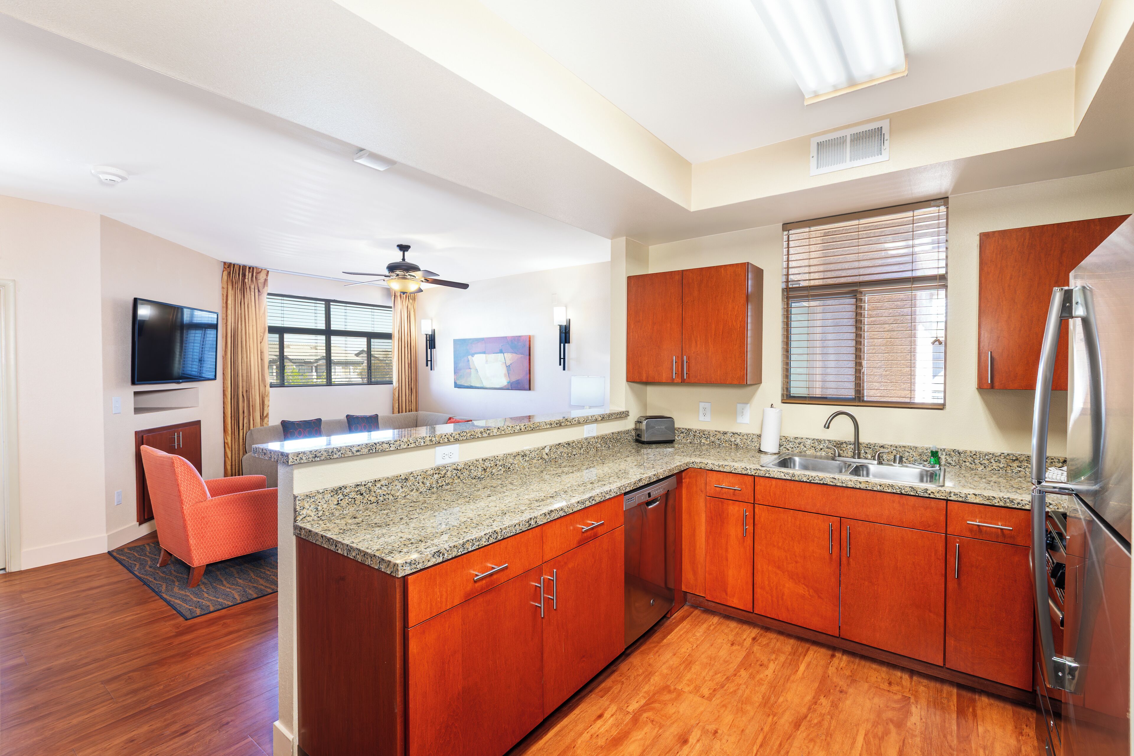 A modern kitchen with wooden cabinets, granite countertops, and stainless steel appliances.