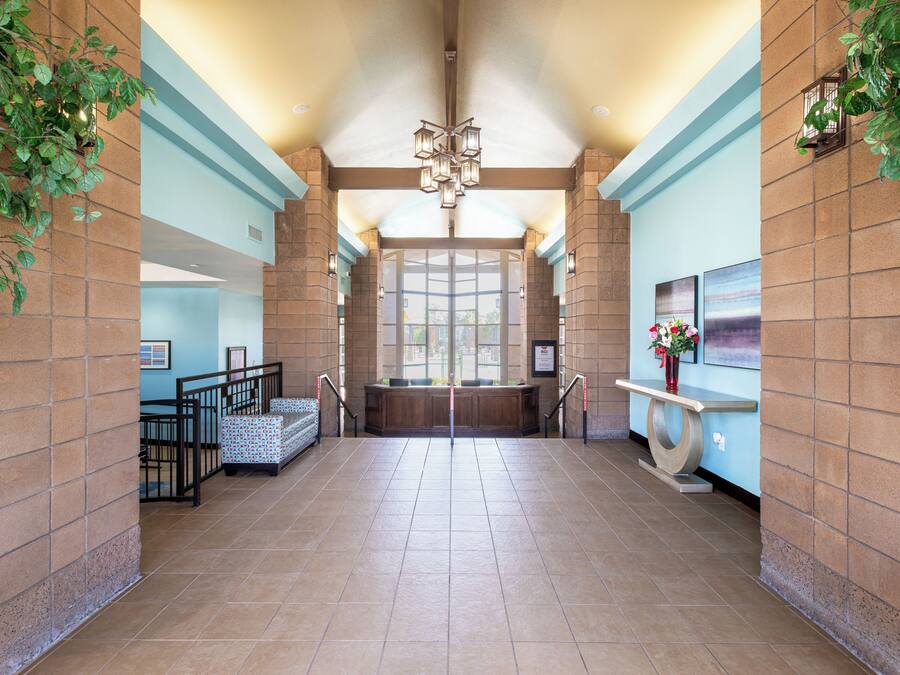 A spacious lobby with a high ceiling, a central staircase, and a reception desk.
