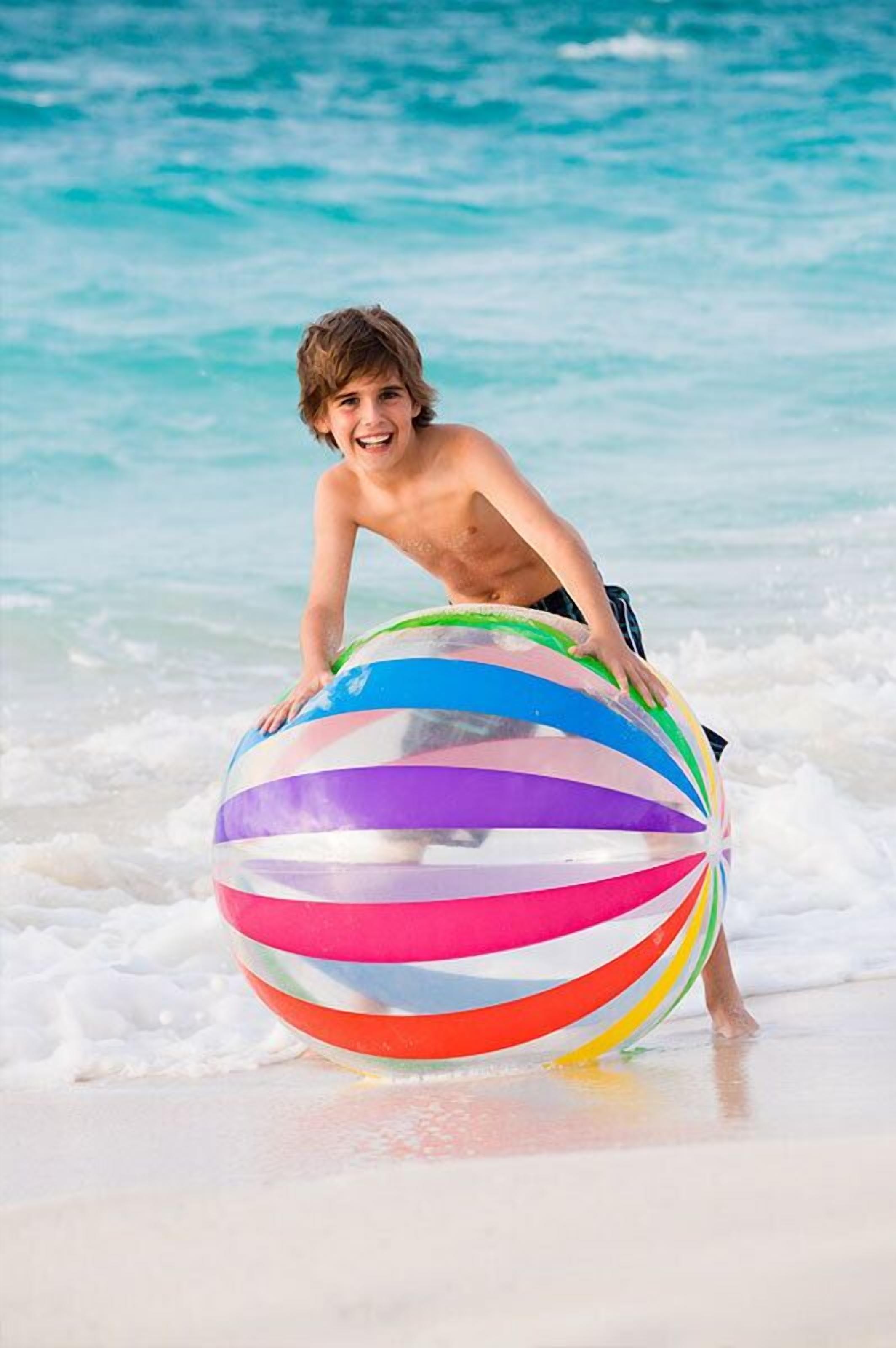 A person on a beach with a colorful striped ball.