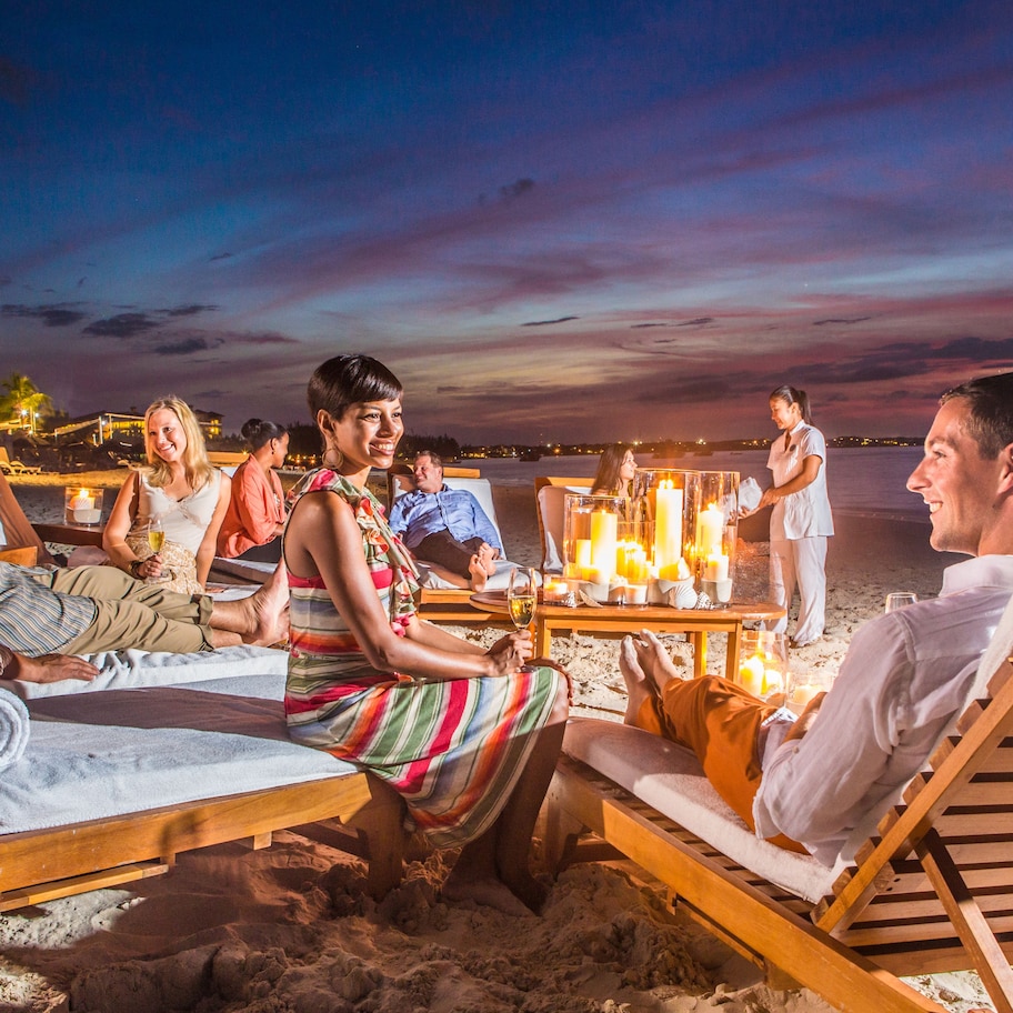 A beachside lounge area with sun loungers and a table with candles.