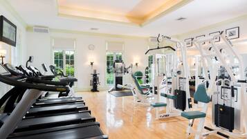 Une salle de sport équipée de tapis de course, d’appareils de musculation et de tapis de sol pour les exercices.