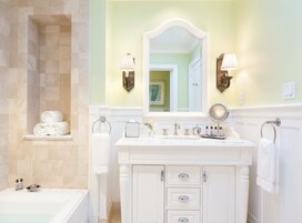 Un baño con bañera, tocador con espejo y un perchero para toallas.