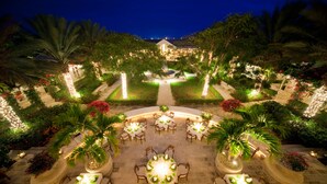 Un espace de restauration en plein air, avec des tables et des chaises disposées en cercle, entouré d’une végétation luxuriante et agrémenté d’un éclairage décoratif.