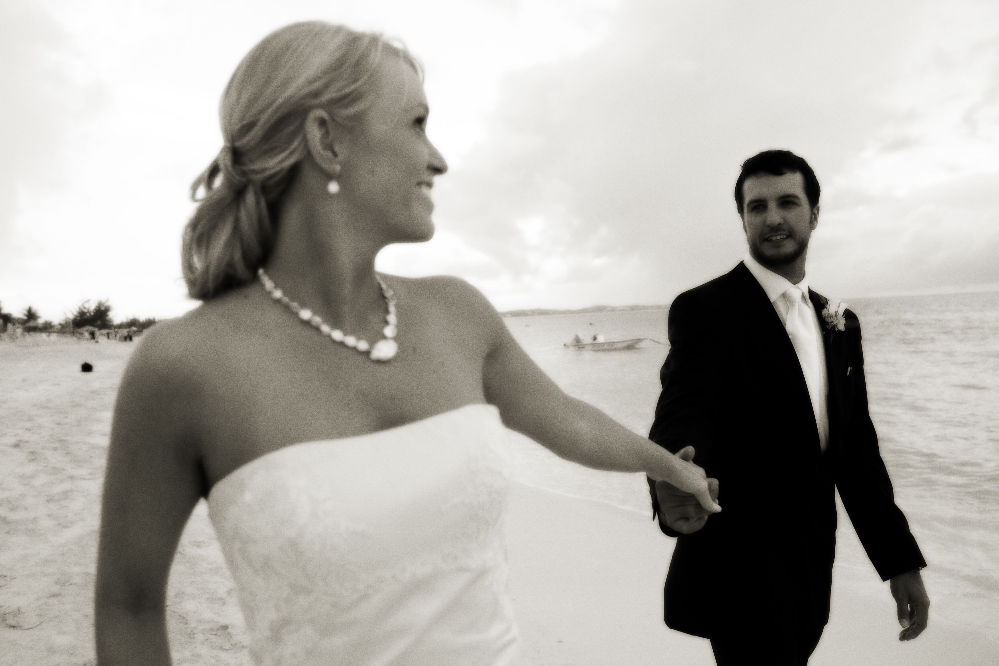 A wedding couple on a beach with a boat in the background.