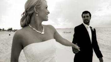 A wedding couple on a beach with a boat in the background.