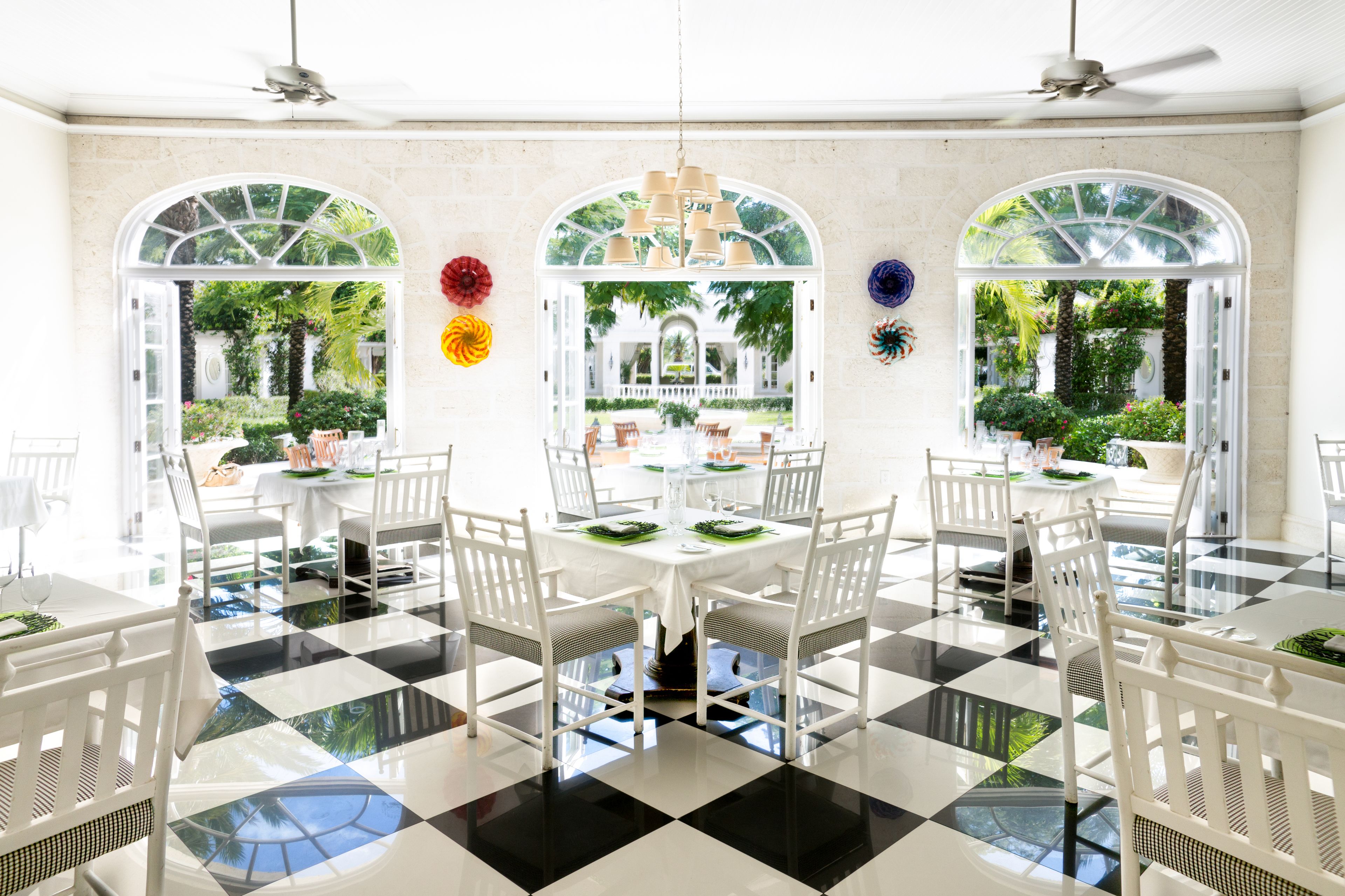 A dining area with a checkered floor, white tables, and chairs.