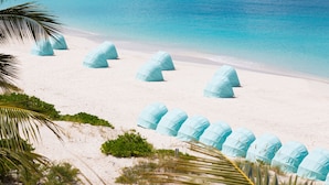 Une plage où plusieurs tentes bleu clair sont disposées en rangée.