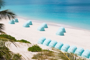 En la playa, arena blanca, sillas reclinables de playa, toallas de playa