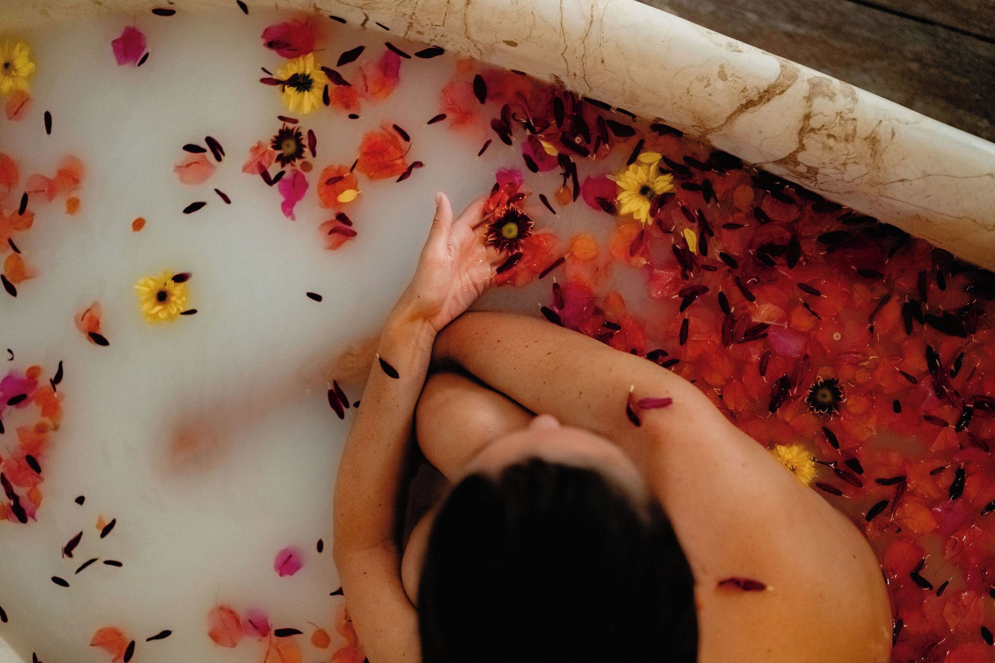 A bathtub filled with water and flower petals.