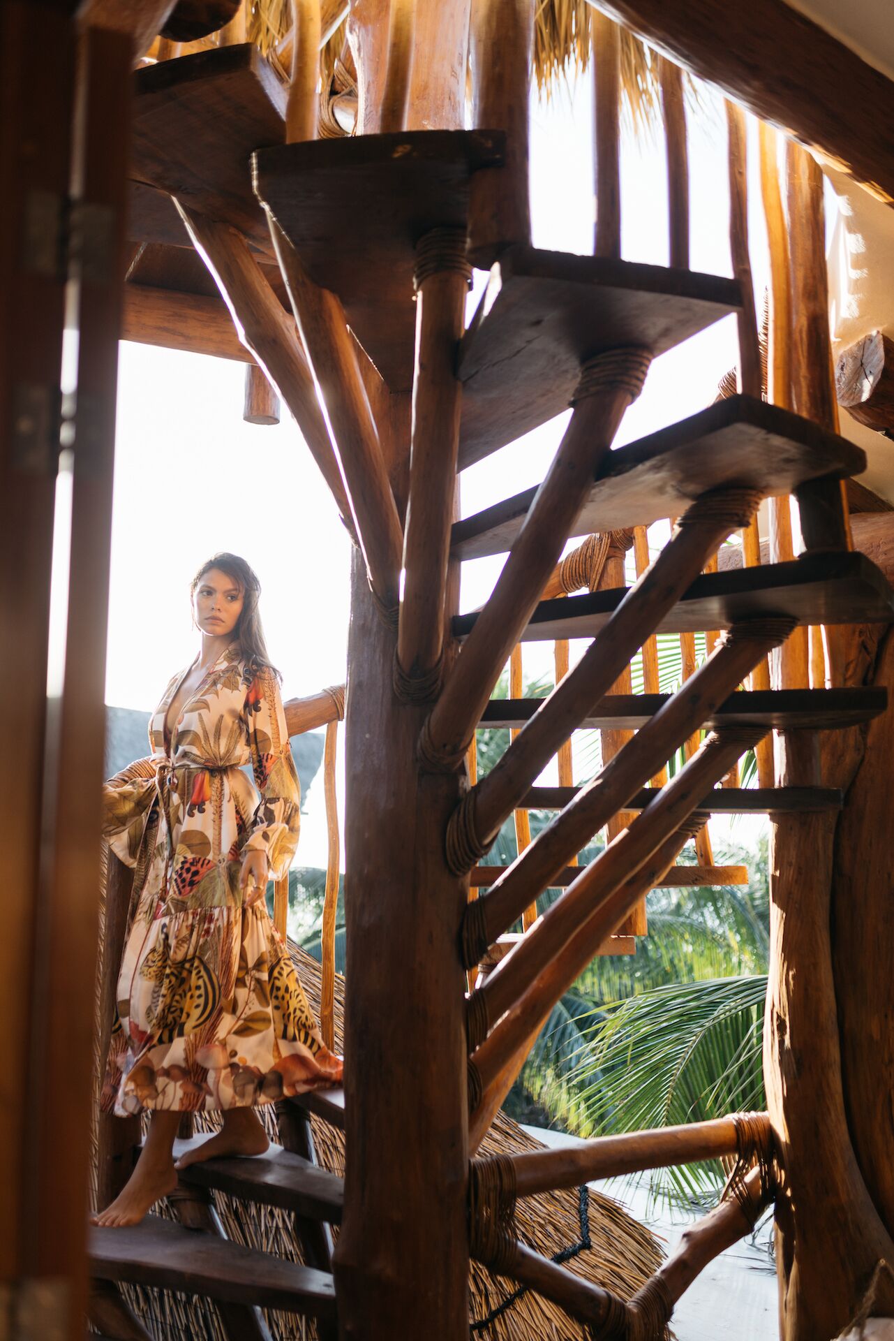 A person standing on a wooden staircase with a view of palm trees.