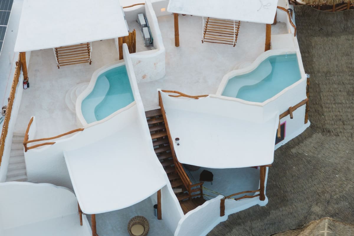 A rooftop pool area with multiple seating areas and a staircase leading to an upper deck.