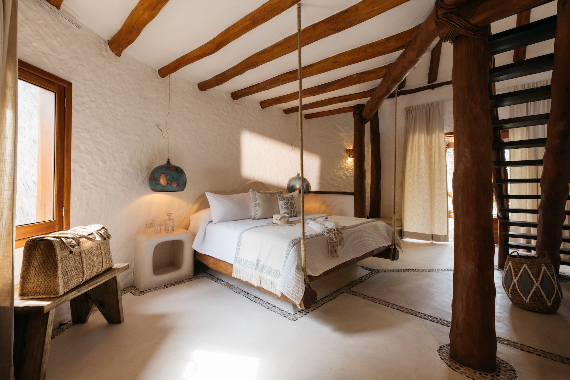 Une chambre à coucher avec un lit, une table de chevet, une lampe suspendue et un escalier en bois.