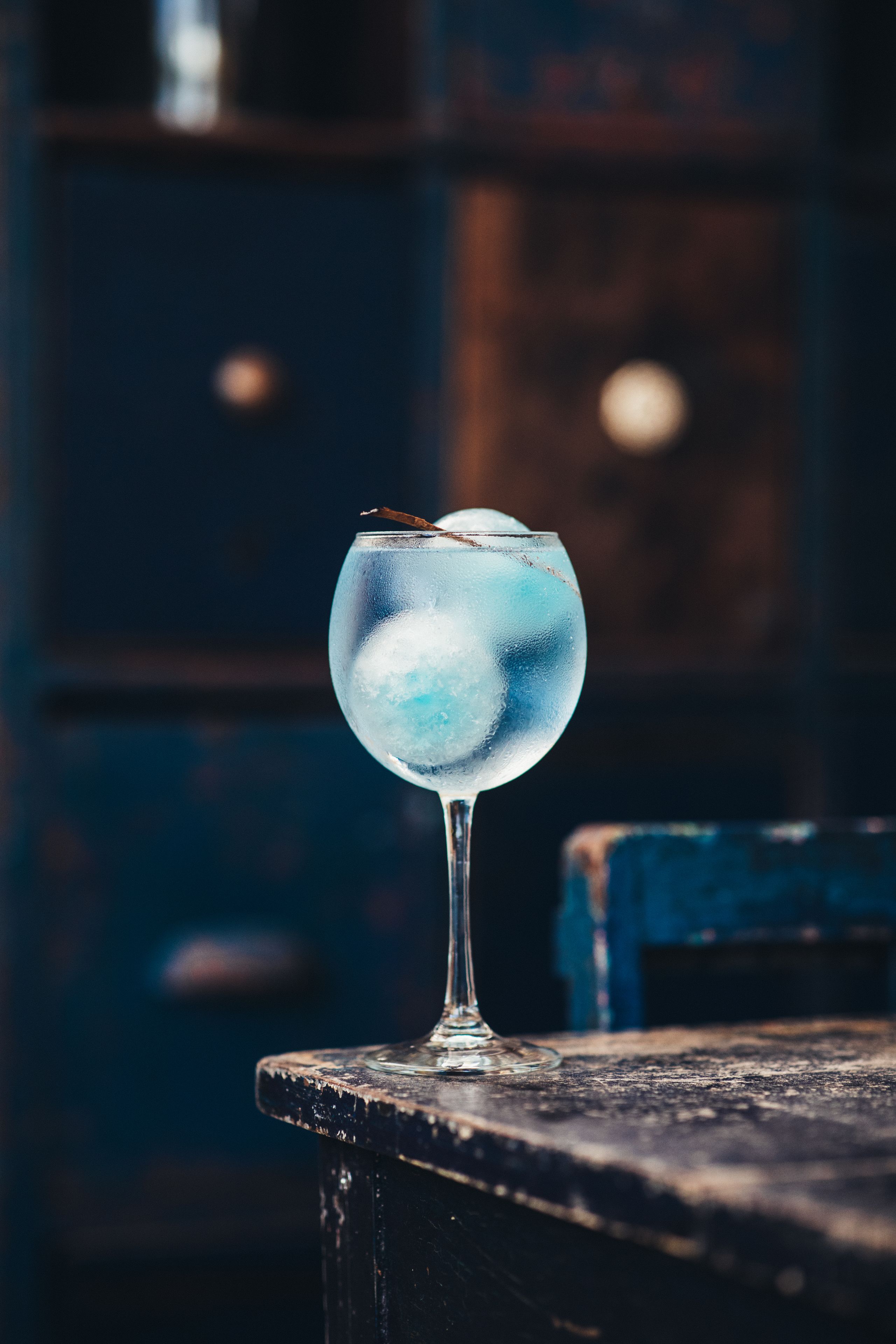 Un vaso transparente con una bebida azul sobre una superficie de madera.
