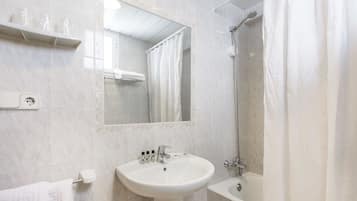 Un baño con lavamanos, espejo, ducha y toallero.