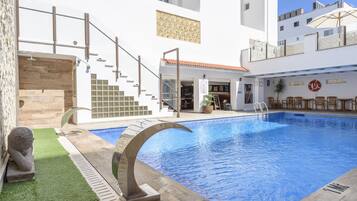 Een buitenzwembad, ligstoelen bij het zwembad