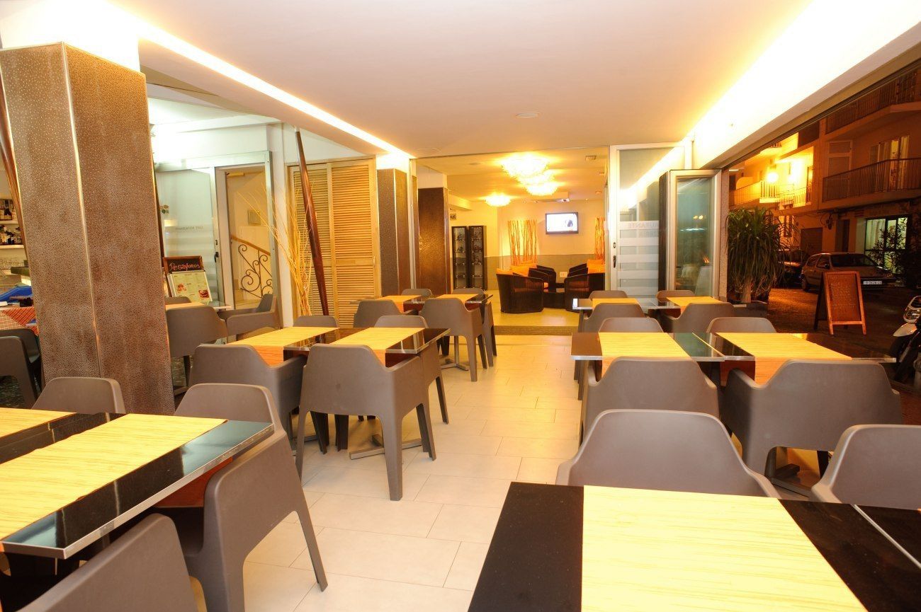 Un comedor moderno con mesas, sillas, una escalera y una zona de bar.