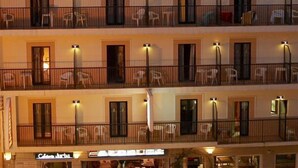 Un hotel de varios pisos con balcones, cada uno con barandilla y una silla.