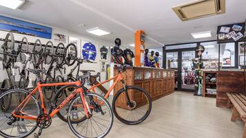 A bicycle shop with multiple bikes on display, a wooden counter, and a view of the street outside.