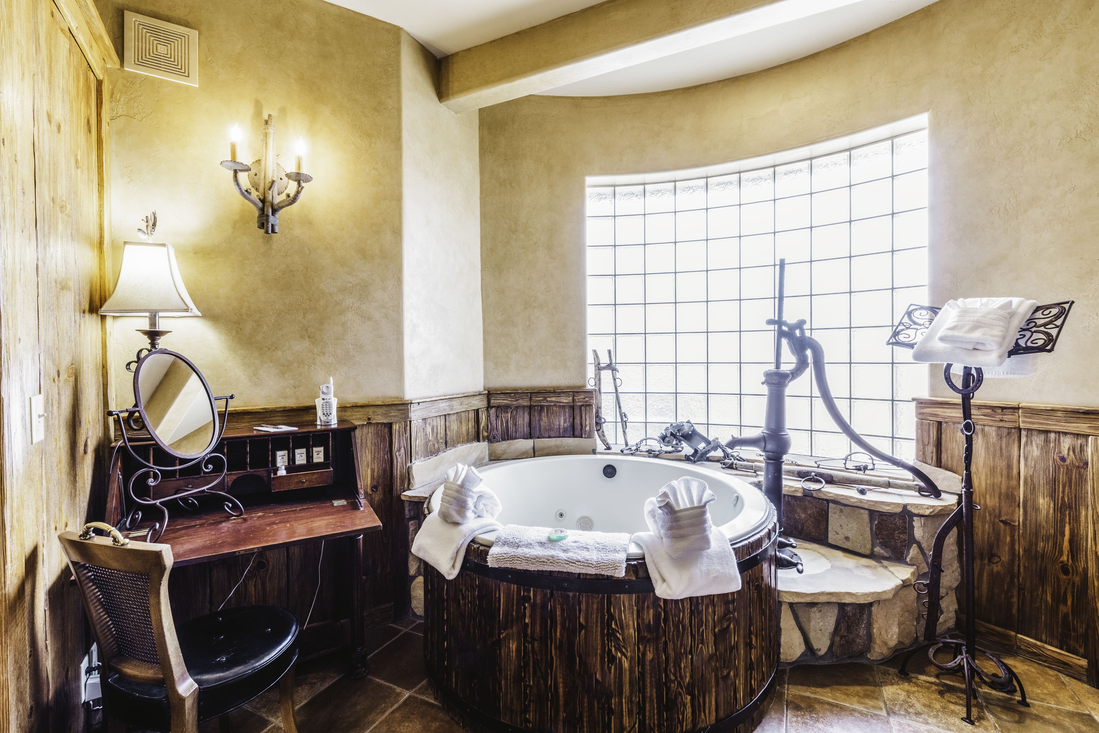 Ein Badezimmer mit freistehender Badewanne, einem Holzwaschtisch, einem Spiegel, einem Handtuchhalter und einem Fenster mit Gittermuster.