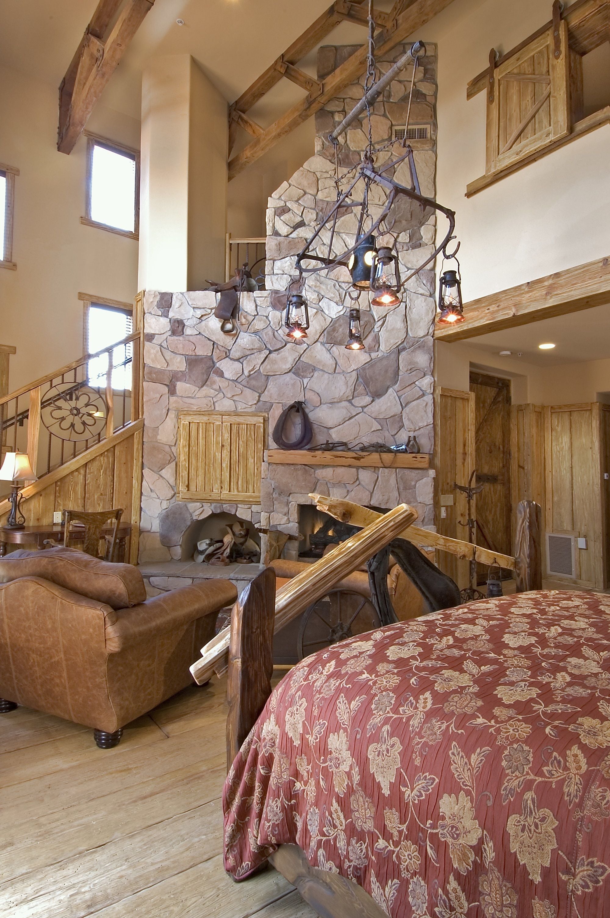 A spacious living area with a stone fireplace, wooden beams, and a large bed.