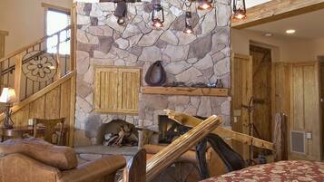 A spacious living area with a stone fireplace, wooden beams, and a large bed.