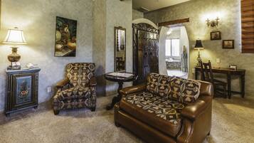 A living room with a brown leather sofa, patterned armchair, and a small round table with a lamp.