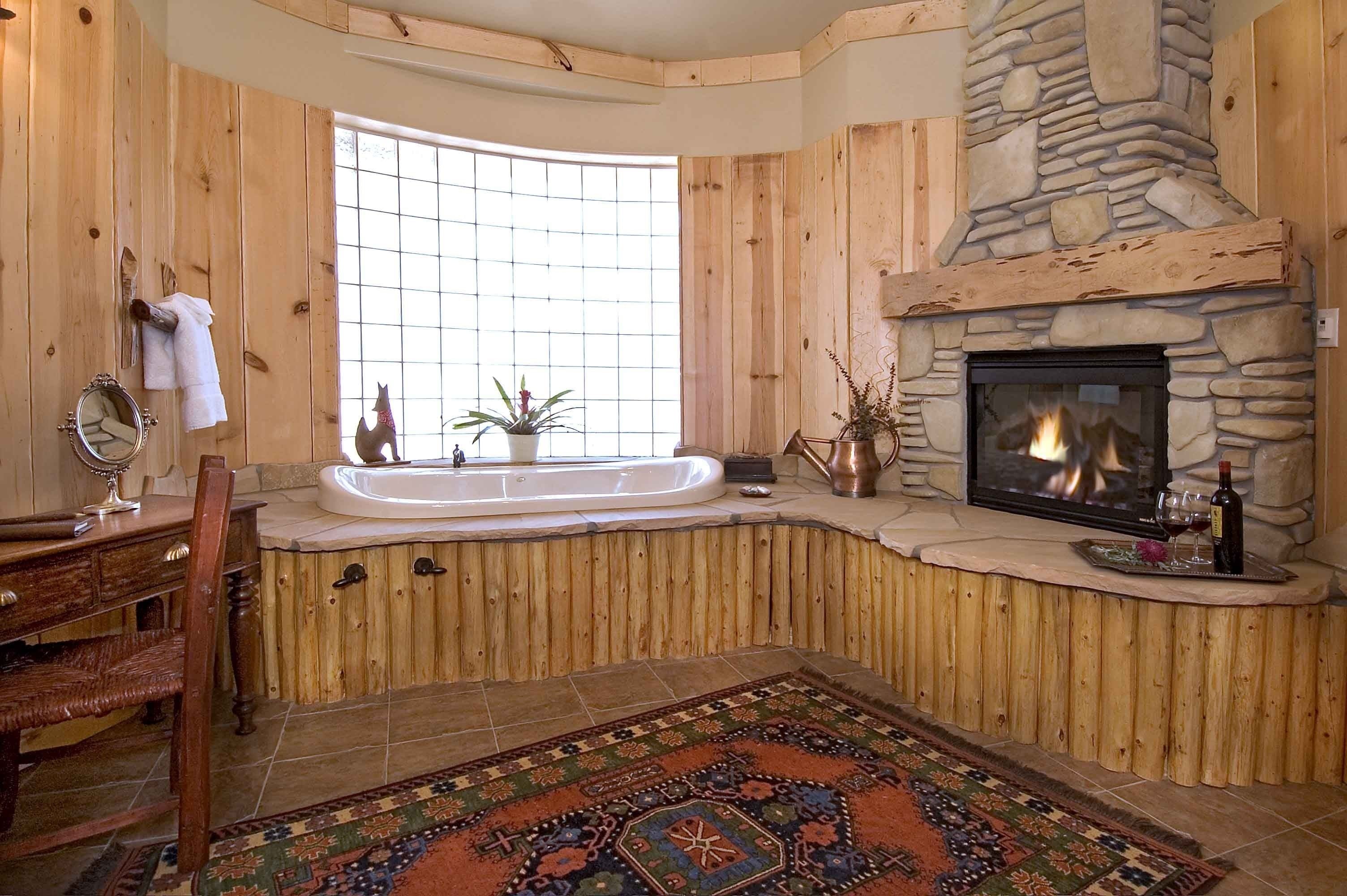 A wooden interior with a stone fireplace, a bathtub, and a rug.