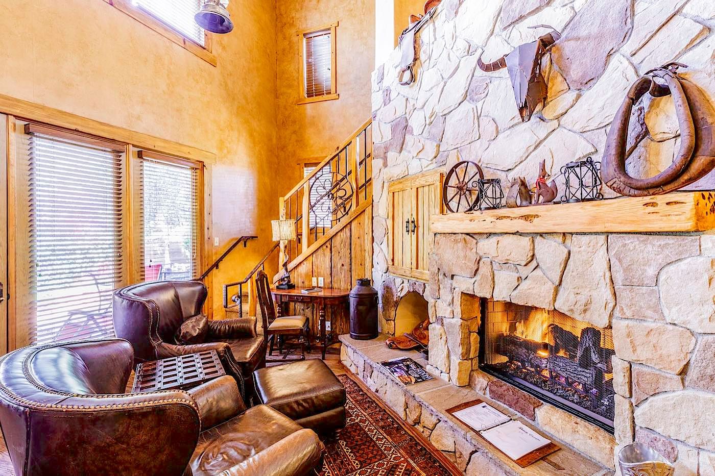 A cozy interior with a stone fireplace, leather seating, and a staircase.