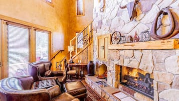 A cozy interior with a stone fireplace, leather seating, and a staircase.