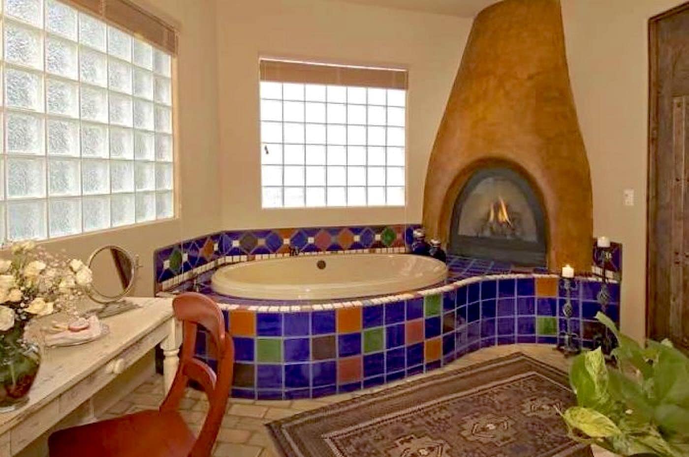 Une salle de bain avec une baignoire sur pieds, un mur décoré d’une mosaïque, une cheminée et une fenêtre.