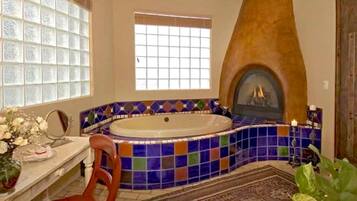 Une salle de bain avec une baignoire sur pieds, un mur décoré d’une mosaïque, une cheminée et une fenêtre.