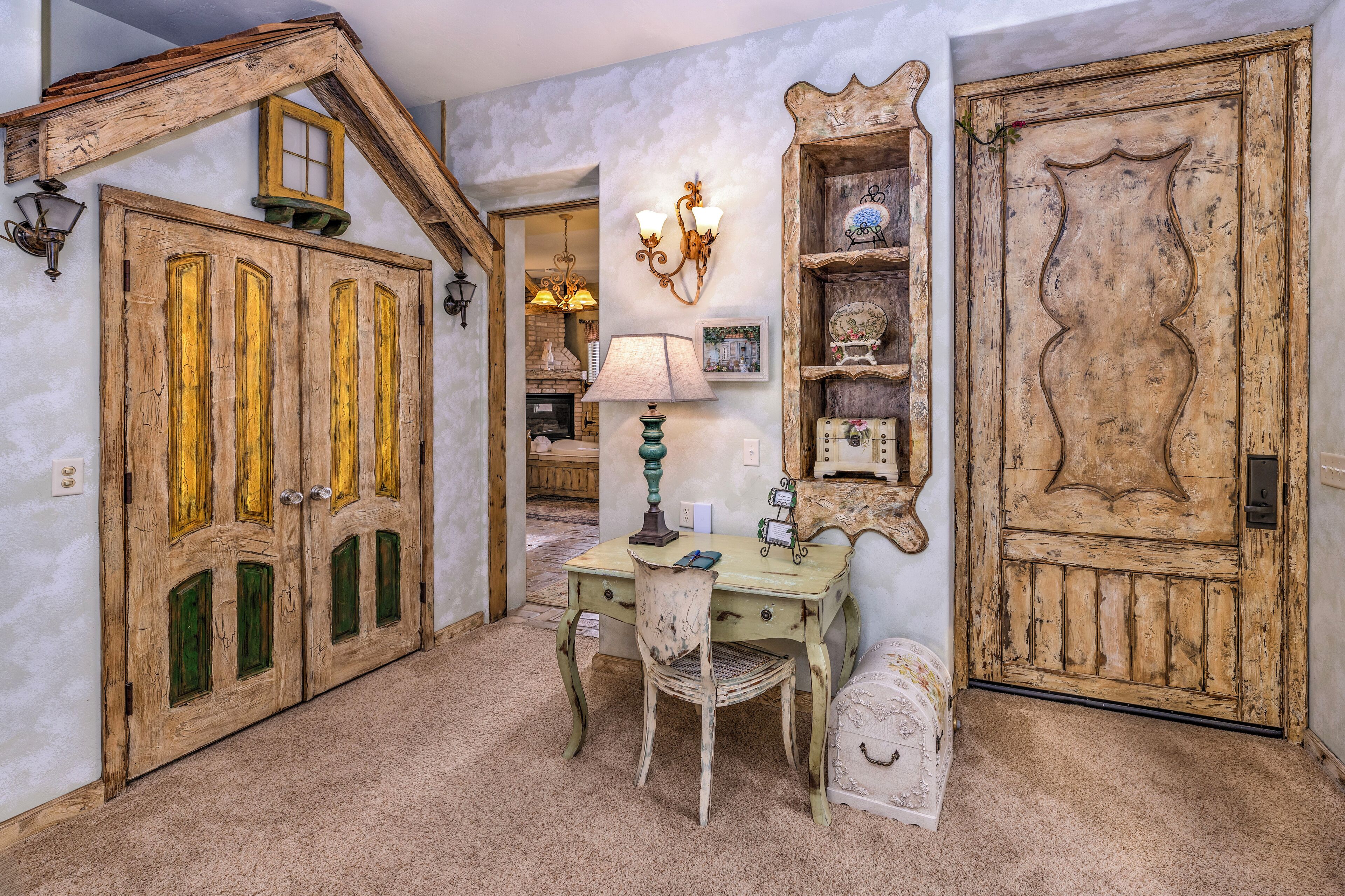 Una habitación con una puerta de madera rústica, una mesa antigua con una lámpara y una silla.