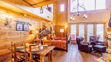 Un interior rústico de madera con un comedor, una cama y una zona de estar.