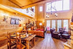 A rustic wooden interior with a dining area, a bed, and a seating area. - Adobe Grand Villas (Sedona)
