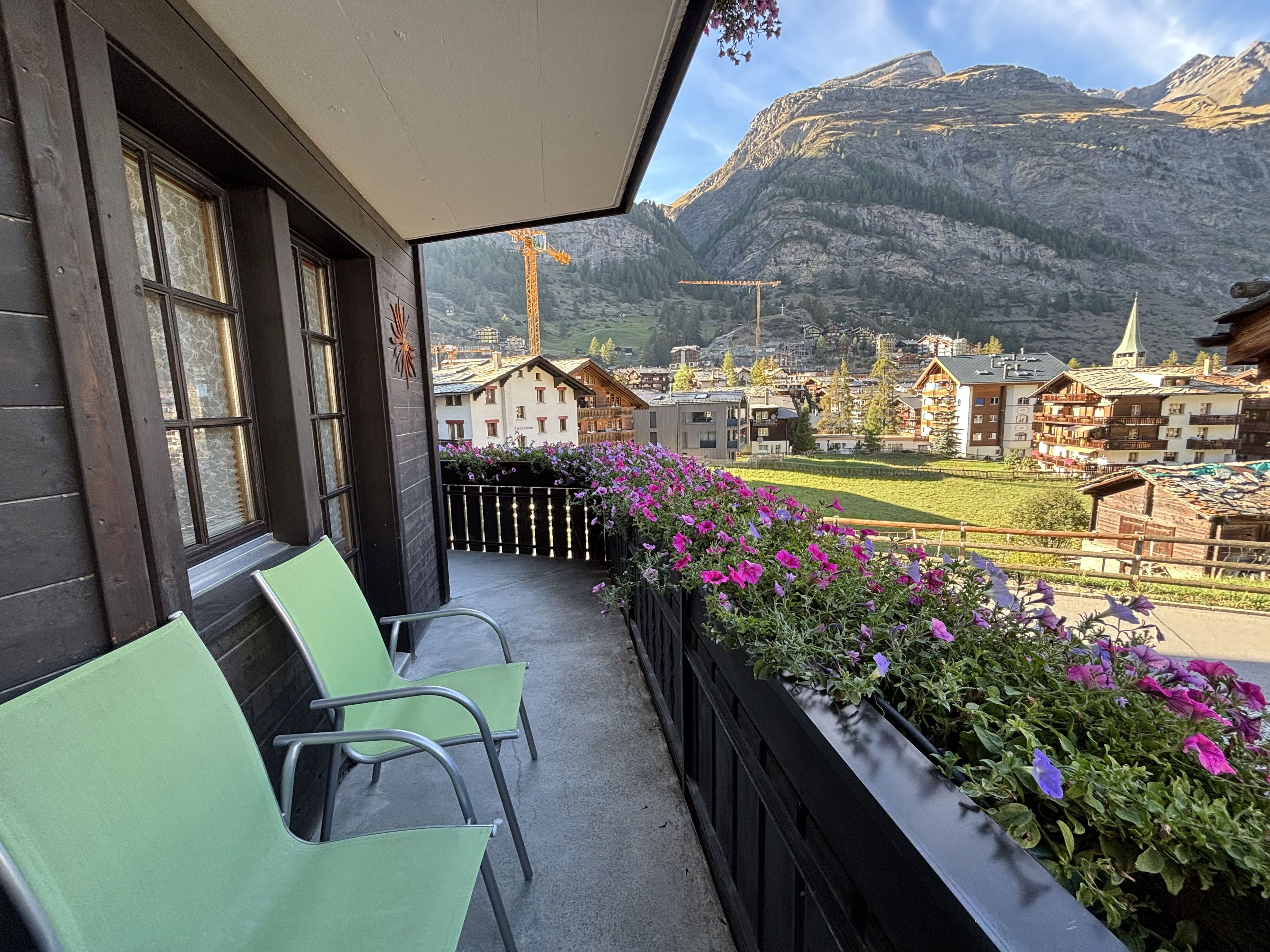 Un balcone con sedie e fioriere affacciato su un villaggio montano.