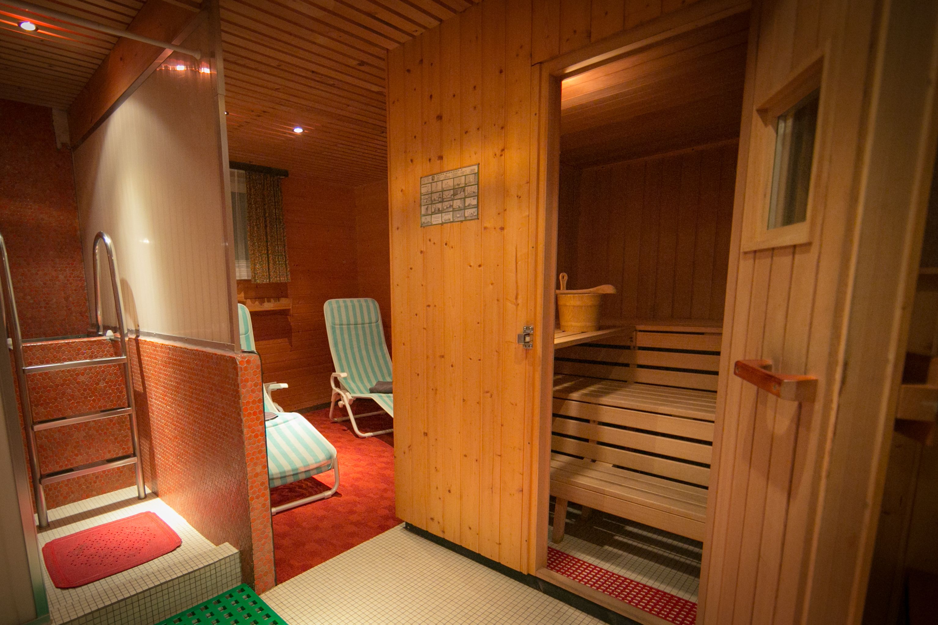 Un sauna avec des murs en bois, un banc, une chaise et une échelle.