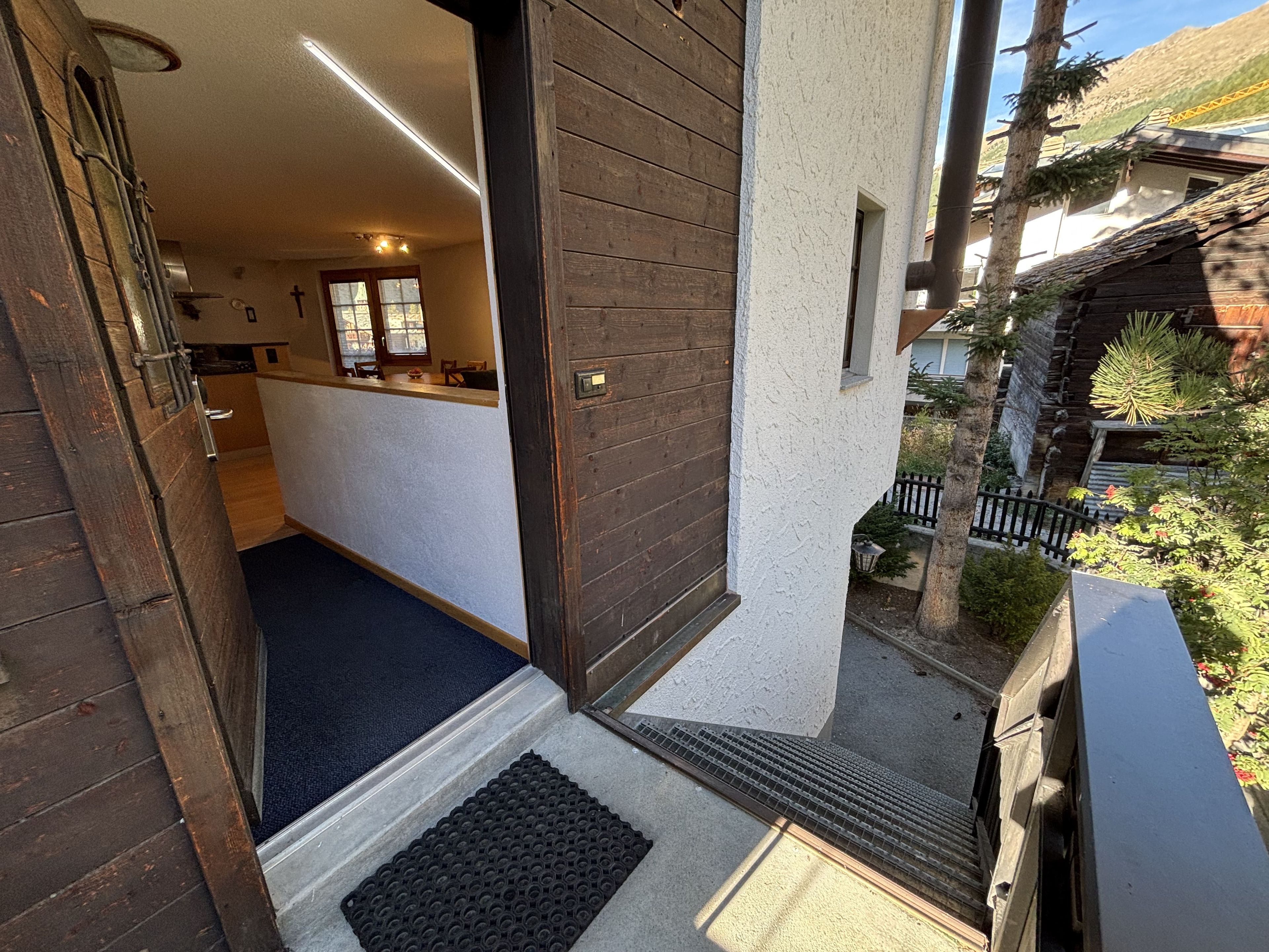 A wooden exterior door leading to a kitchen area with a visible countertop and a window.
