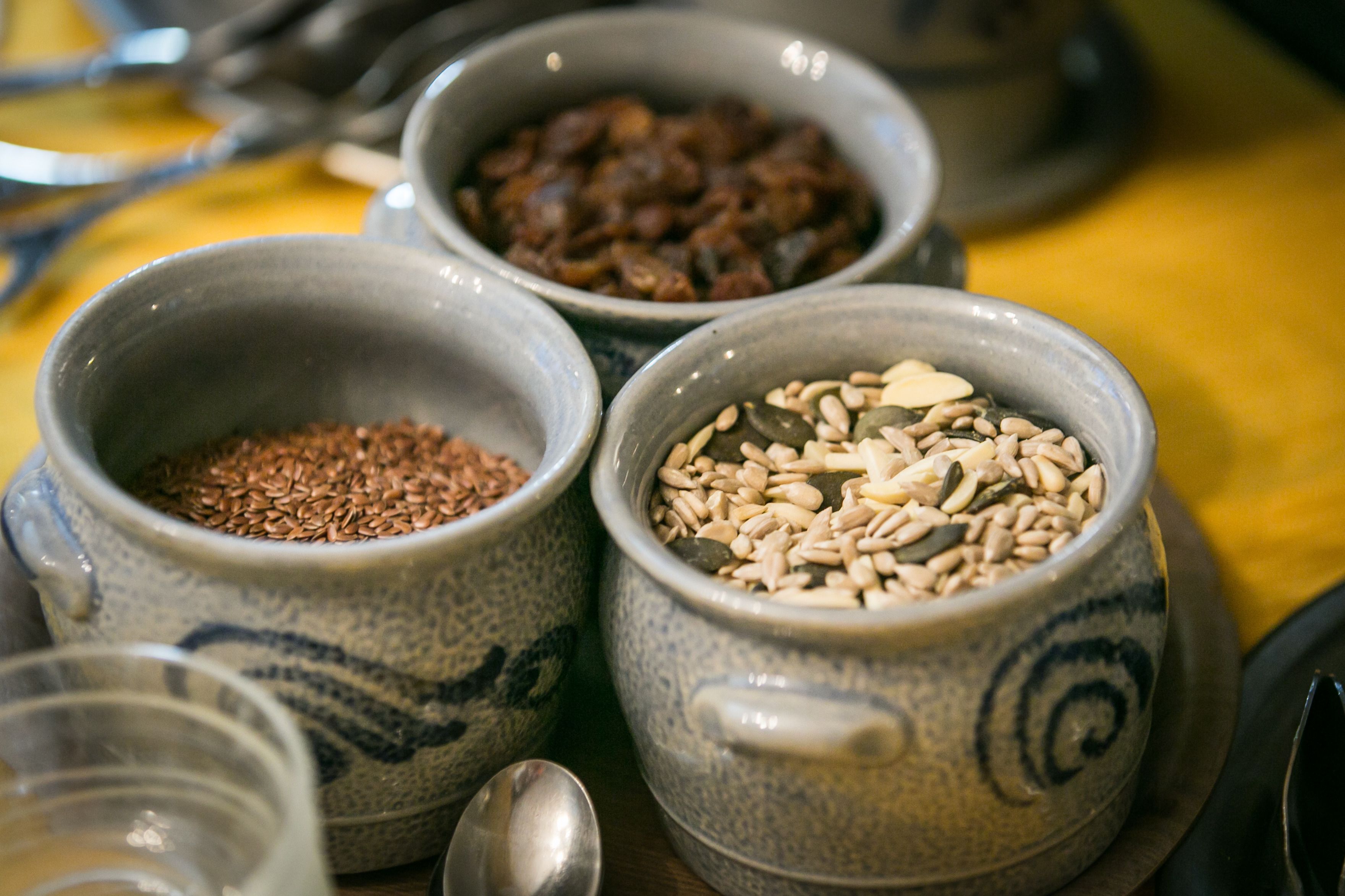 Three ceramic bowls containing different grains on a table.