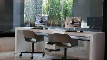 A modern office space with two HP desktop computers, a glass desk, and two office chairs.
