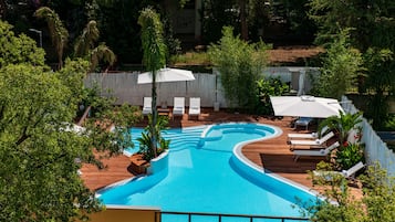 Relax by the serene pool surrounded by lush greenery and shaded seating areas.