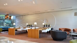 Un área de recepción moderna con una pared curva, mostrador de recepción, sillas blancas y diversas opciones de asientos, incluyendo sofás y sillones.