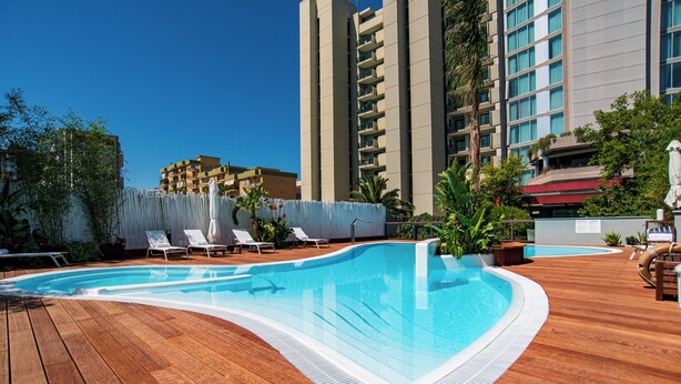 Una piscina con cubierta de madera, rodeada de sillas de descanso y plantas en macetas.