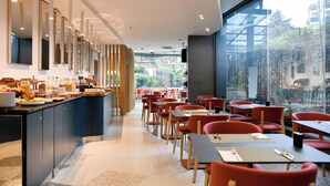 Un comedor moderno con bufé, sillas rojas y vistas al verde exterior.
