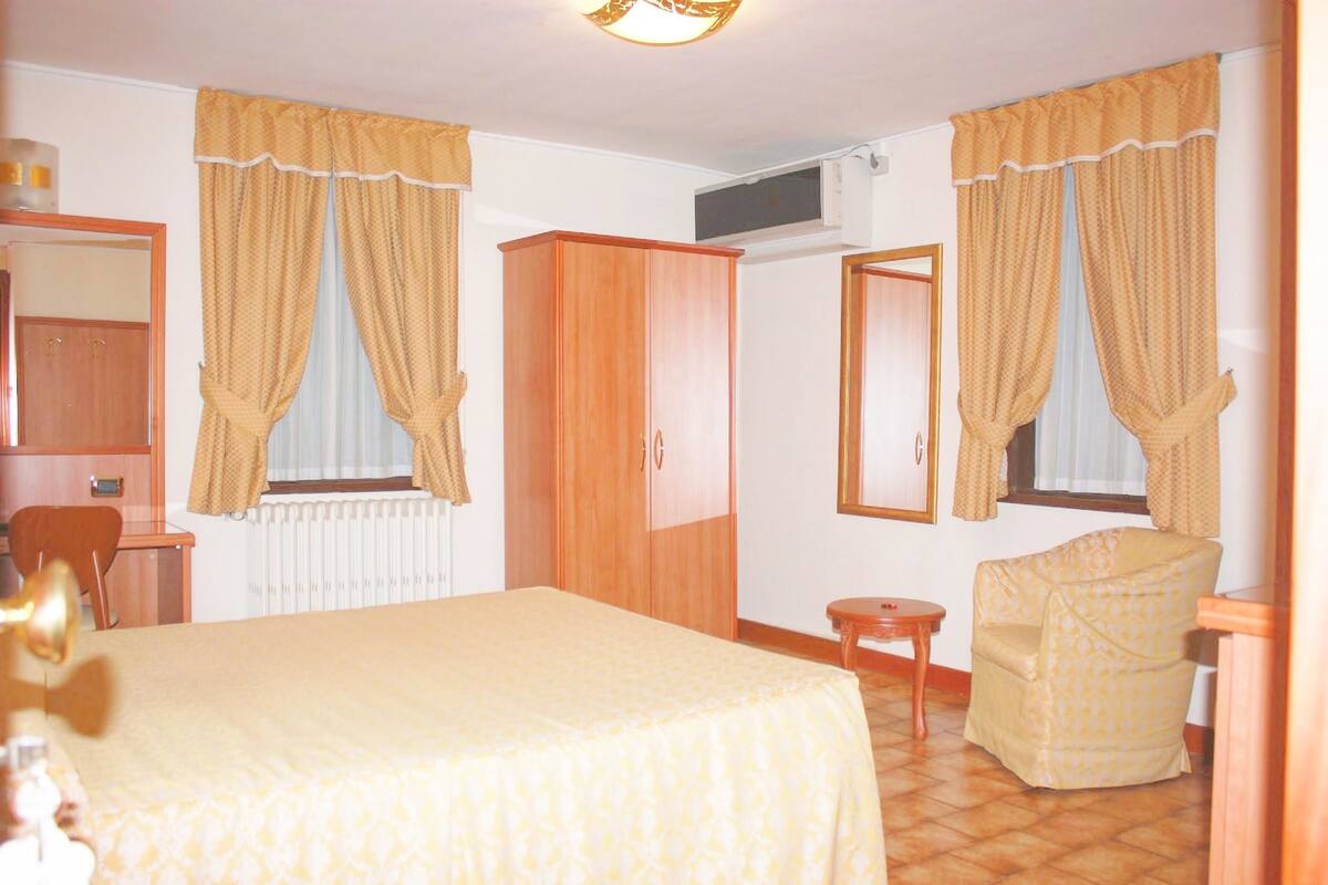 Une chambre d’hôtel avec un lit, une armoire en bois, une chaise et une petite table.