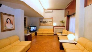 A living room with a sofa set, a television, and a painting on the wall. - Piccolo Hotel (Milan)