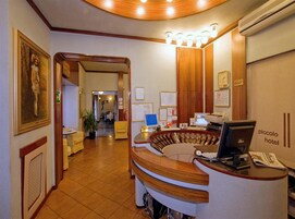 Een hotel receptie met een gebogen balie, een computer en een klok aan de muur.