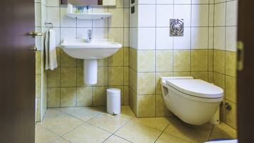 Een badkamer met een wastafel, toilet en afvalbak.