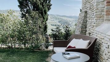 A patio with wicker furniture, a round table, and a view of the countryside.