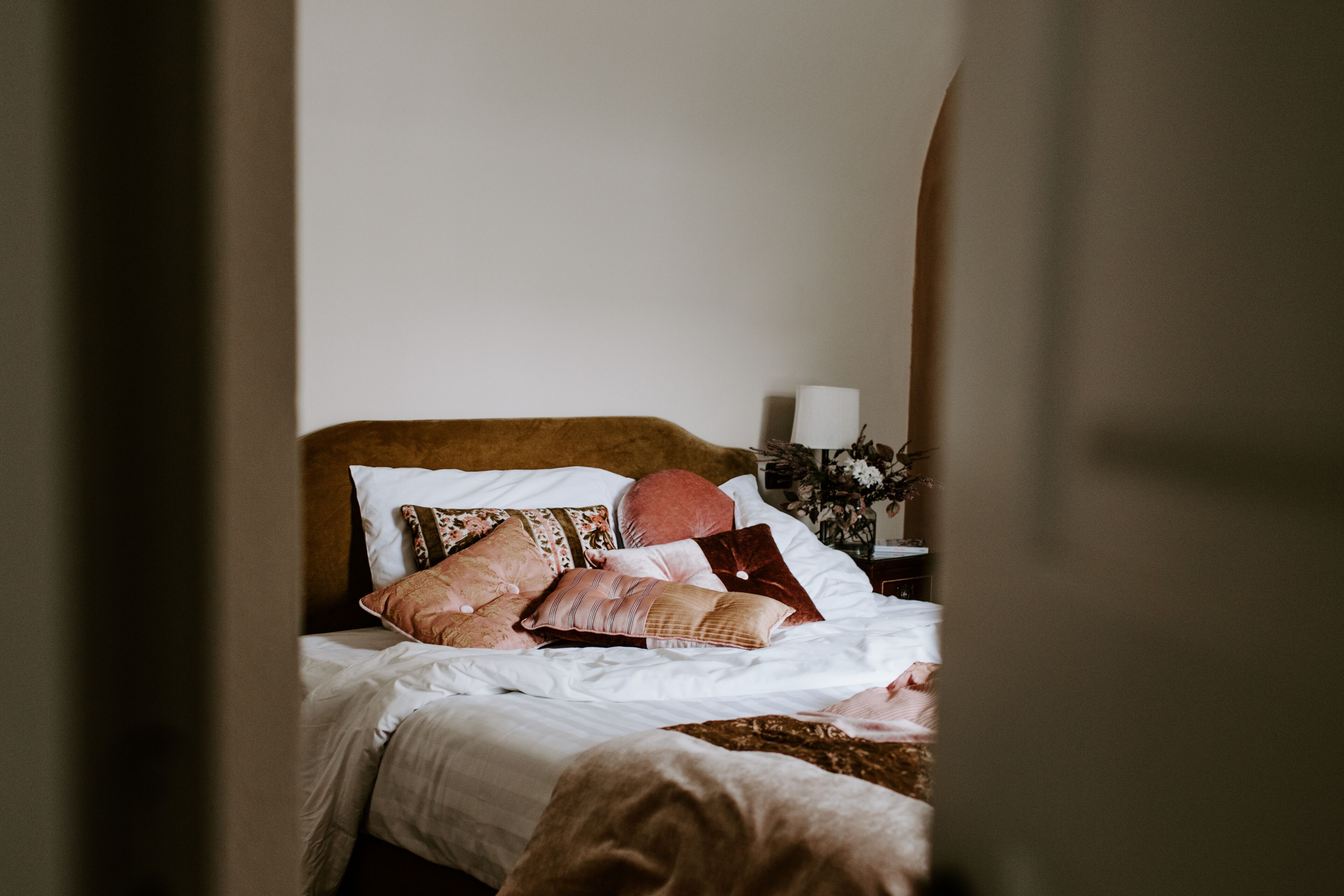 Una cama con muchas almohadas y una colcha blanca.