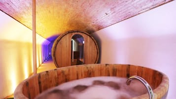 A wooden bathtub with steam, a brick ceiling, and a wooden barrel-shaped door.